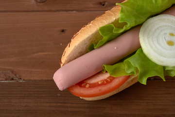 sandwich with sausage and vegetables on a wooden table
