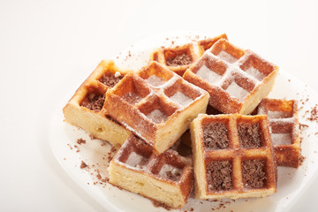 Belgian waffles with grated chocolate and icing on a white plate