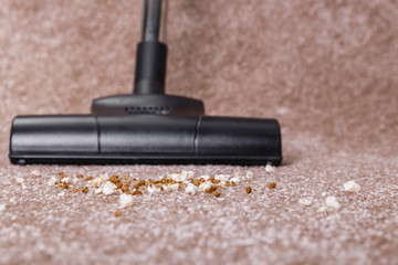 Vacuuming carpet with vacuum cleaner. Dirt on the rug. Housework service. Close up of the head of a sweeper cleaning device.