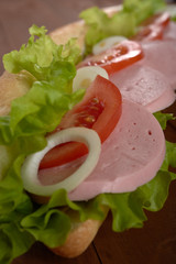 sandwich with sausage and vegetables on a wooden table