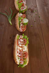 sandwich with sausage and vegetables on a wooden table