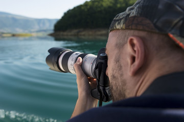 Obraz premium Photographer in nature taking pictures to a beautiful lake