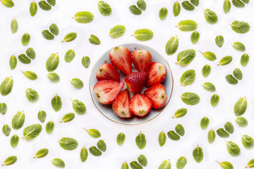 
Bowl with cut strawberries on white background with spearmint leaves,