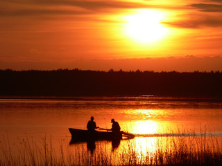 Bright orange sunset on the lake. Fishermen catch fish