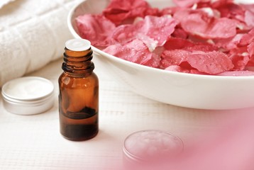 Aromatic body care at-home spa. Bowl of pink rose petals, essential oil, facials. Natural flower blur effect, pastel toned. 