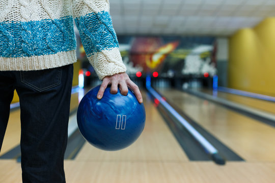 Man holds ball at bowling lane, cropped image