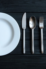 Plate on the table. Fork and knife. Black textures. Crockery in the kitchen. Home comfort.