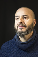 Handsome, bald man with beard on black background