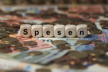 spesen - Holzwürfel mit Buchstaben im Hintergrund mit Geld, Geldscheine