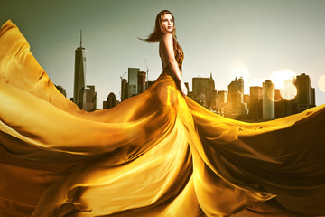Frau mit langem goldenen Kleid vor Skyline