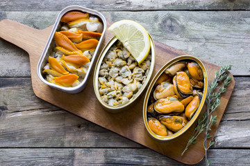   Cans of preserves with clams, cockles and mussels on a rustic table