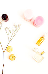 Natural cosmetics, organic oils for face, hair and body, macaroons, pink candles, flowers. Flat lay for beauty blog on a white. Copy space