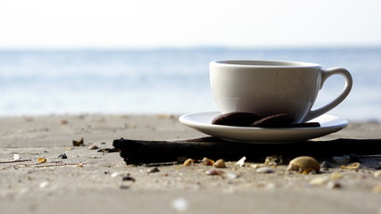 Espresso coffee and chocolate cookies. A cup of latte, cappuccino or espresso coffee on the beach.