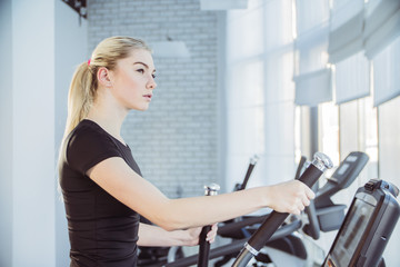 Fototapeta premium beautiful young girl is engaged in sports and fitness she runs on the simulator treadmill 
