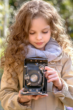  Little girl with old retro photography camera in hands outdoors