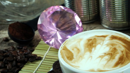 Cappuccino coffee and chocolate cookies. A cup of latte, cappuccino or espresso coffee with milk put on a wood table with dark roasting coffee beans and cookies. Drawing the foam milk on top.