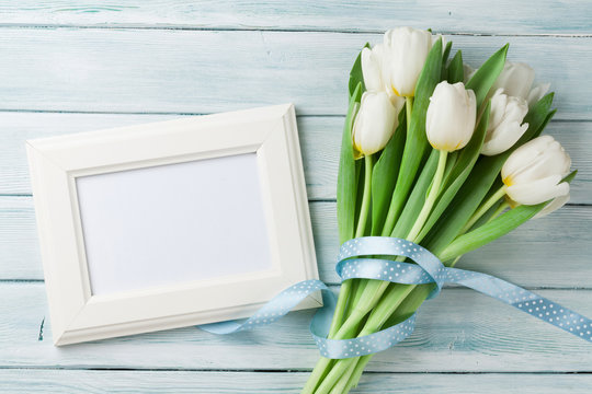 White tulips bouquet and blank photo frame