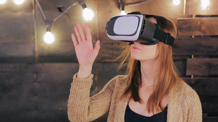 Young woman using Virtual Reality Glasses. Virtual reality mask. VR. Retro loft Christmas background with light bulbs