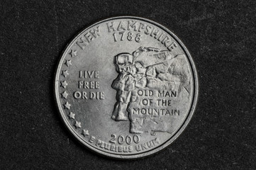 Close up of New Hampshire quarter dollar coin on black background - business concept