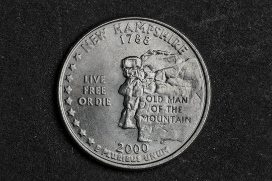 Close up of New Hampshire quarter dollar coin on black background - business concept