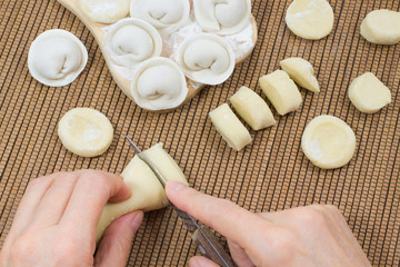 Hands cut the dough into pieces. Raw dumplings on  board