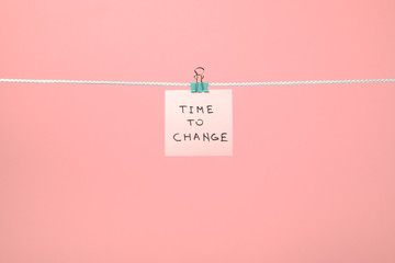 Pink paper note hanging on the string with text “Time to Chang