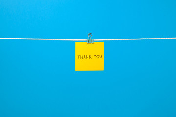 Yellow paper note on clothesline with text “Thank You”