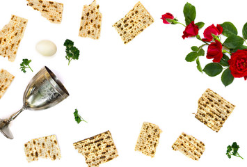 Matzo, wine bowl, parsley, red roses and eggs for passover celebration on white background with space for text. Top view, flat lay