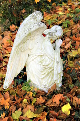 Pomnik klęczącego anioła jesienną porą.