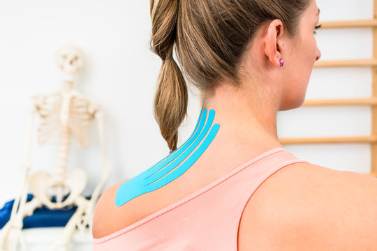 Woman from behind with Kinesio tape on shoulder in physiotherapy