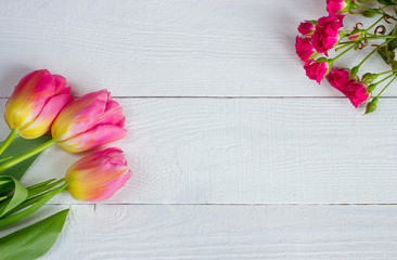 Colorful tulips with miniature roses on wooden table. Top view with copy space