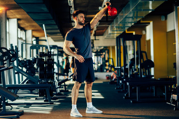 Handsome man lifting a kettlebell in the gym