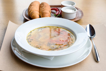 Zama traditional moldovan chicken soup with noodles and vegetables in white bowl, bread, sour cream and red pepper