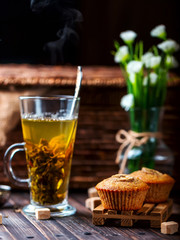 Banana cupcake on a wooden stand. Transparent Cup with green tea