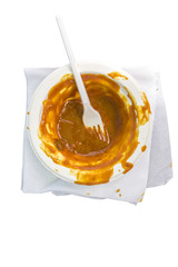 Empty bowl with remains of curry sauce and a plastic fork, isolated on white background