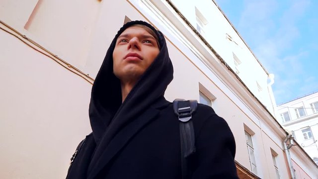 Stylish male tourist walks through the historic district of the city with old buildings pink.