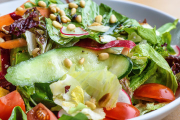 Close up photo of green healthy salad with ruccola, tomatoes, cucumbers, beet and seeds