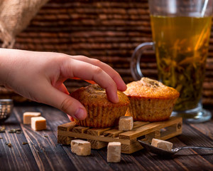 Children's hand takes the banana cupcake. A Cup of tea in the ba