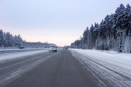 Road winter, evening hours, through the forest