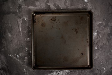 Grey black spotted stone concrete table with a metal baking tray, background, blank