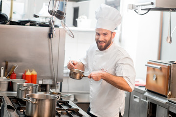Chef cook in uniform cooking soup in the big cooker at the restaurant kitchen