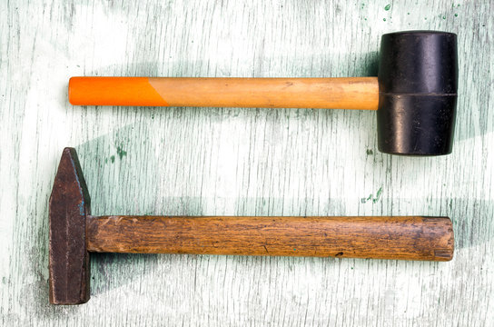 Steel and rubber mallet against a background texture old painted boards.
