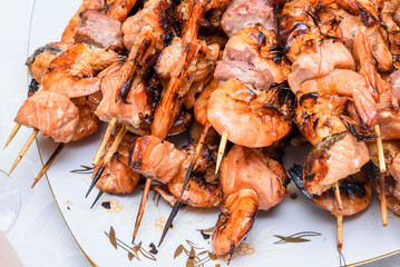 Seafood appetizers mix consisting of red salmon and tuna fish meat and shrimp on plate, close up