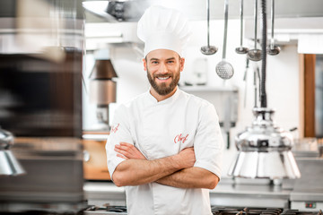 Portrait of handsome positive chef cook at the restaurant kitchen