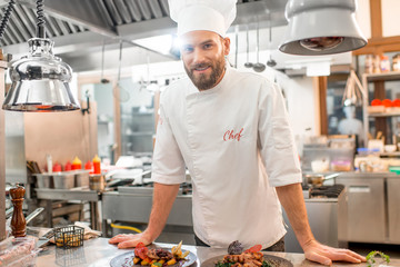 Portrait of chef cook in uniform with prepaired delicious dish at the restaurant kitchen