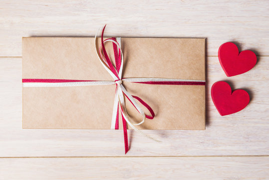 Love letter and red hearts over wooden table