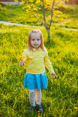 Pretty little girl with dandelions playing outdoors