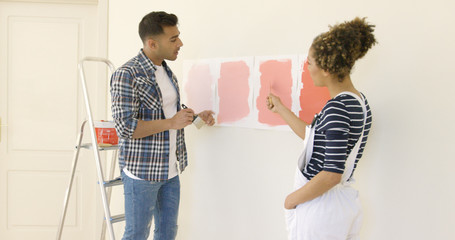 Young couple debating a new paint color for the wall of their home as they embark on a renovation...