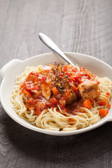 Chicken Cacciatore over pasta in white bowl on dark background vertical shot