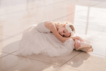 Cute little ballerina in white ballet costume and pointe shoes  posing 
